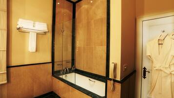 A bathroom with a large mirror, a sink, and a robe hanging on the door.