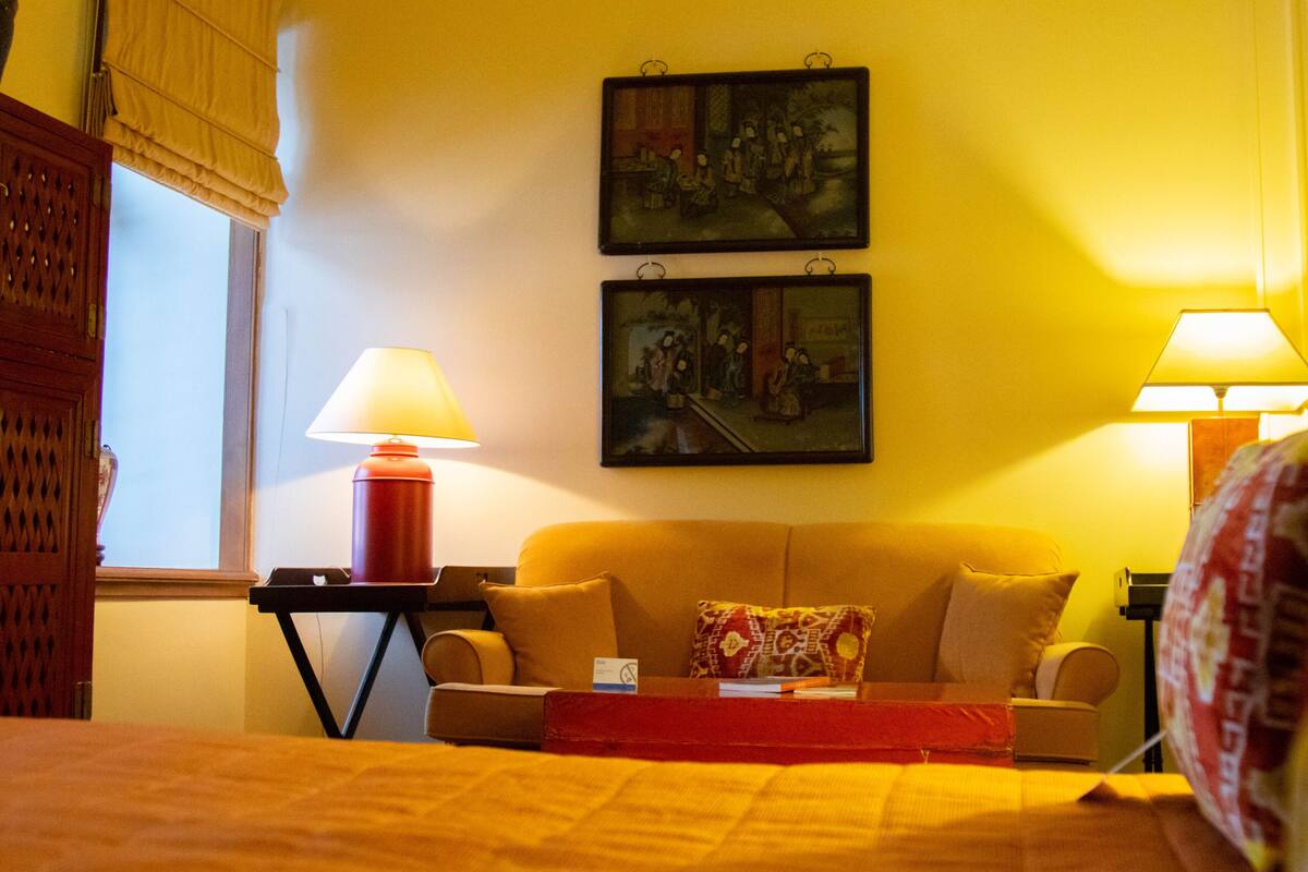 Ein Hotelzimmer mit einem Bett, einer Couch, zwei Wandgemälden und zwei Nachttischlampen.