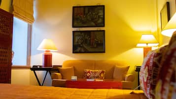 Una habitación de hotel con una cama, un sofá, dos cuadros en la pared y dos lámparas de noche.