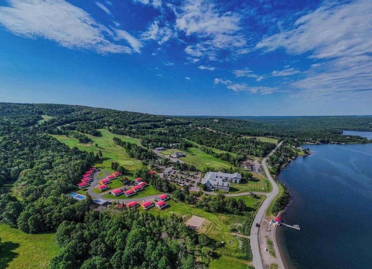 Vista aérea de un complejo turístico con un campo de golf, un lago y un muelle.