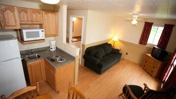 A compact living space with a kitchenette, a sofa, a television, and a dining area.
