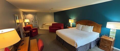 Una habitación de hotel con cama, escritorio, silla y mesita de noche.