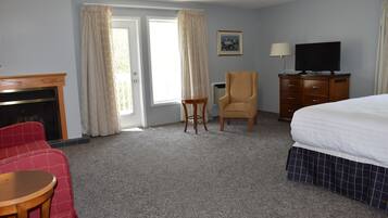 Habitación de hotel con cama, televisión, silla, mesita, cómoda y chimenea.