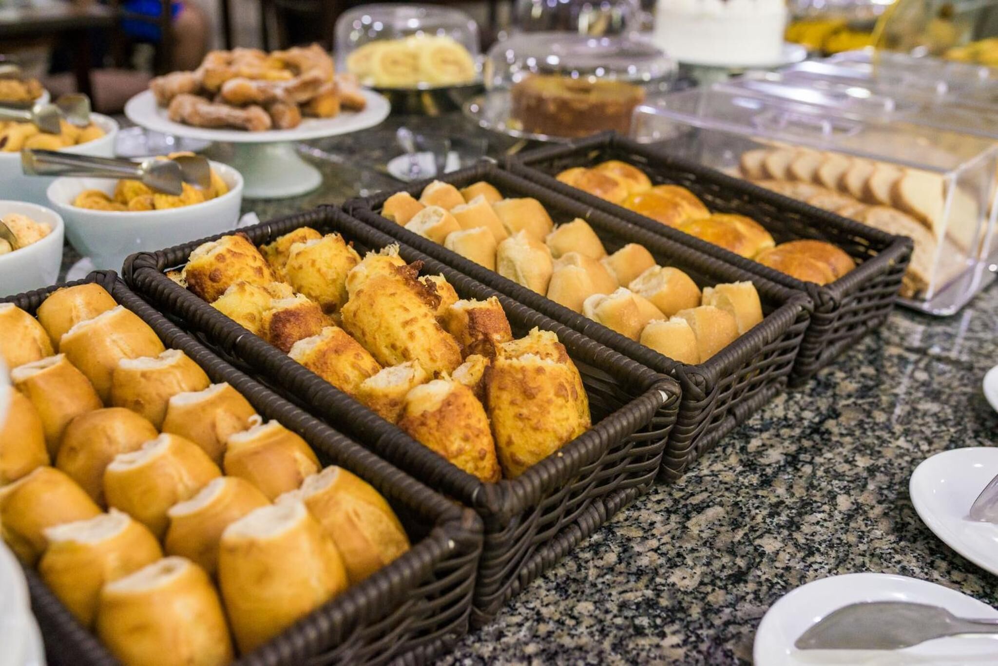 A buffet with various baked goods including bread rolls and pastries.