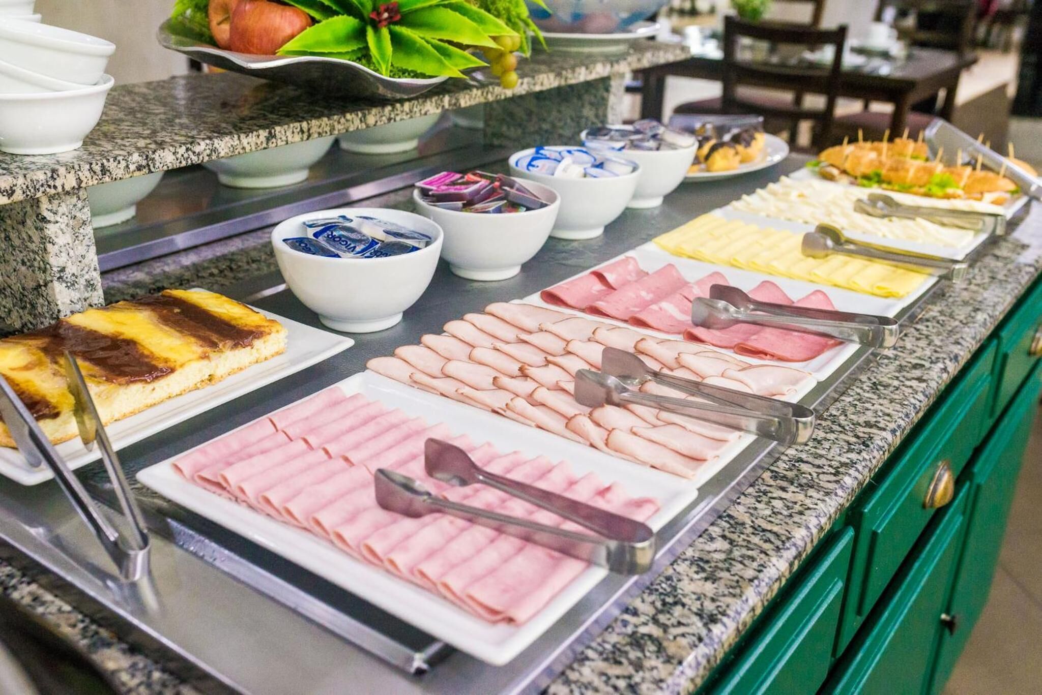 Un bufé con diversas opciones de comida, incluyendo carnes, quesos y postres.