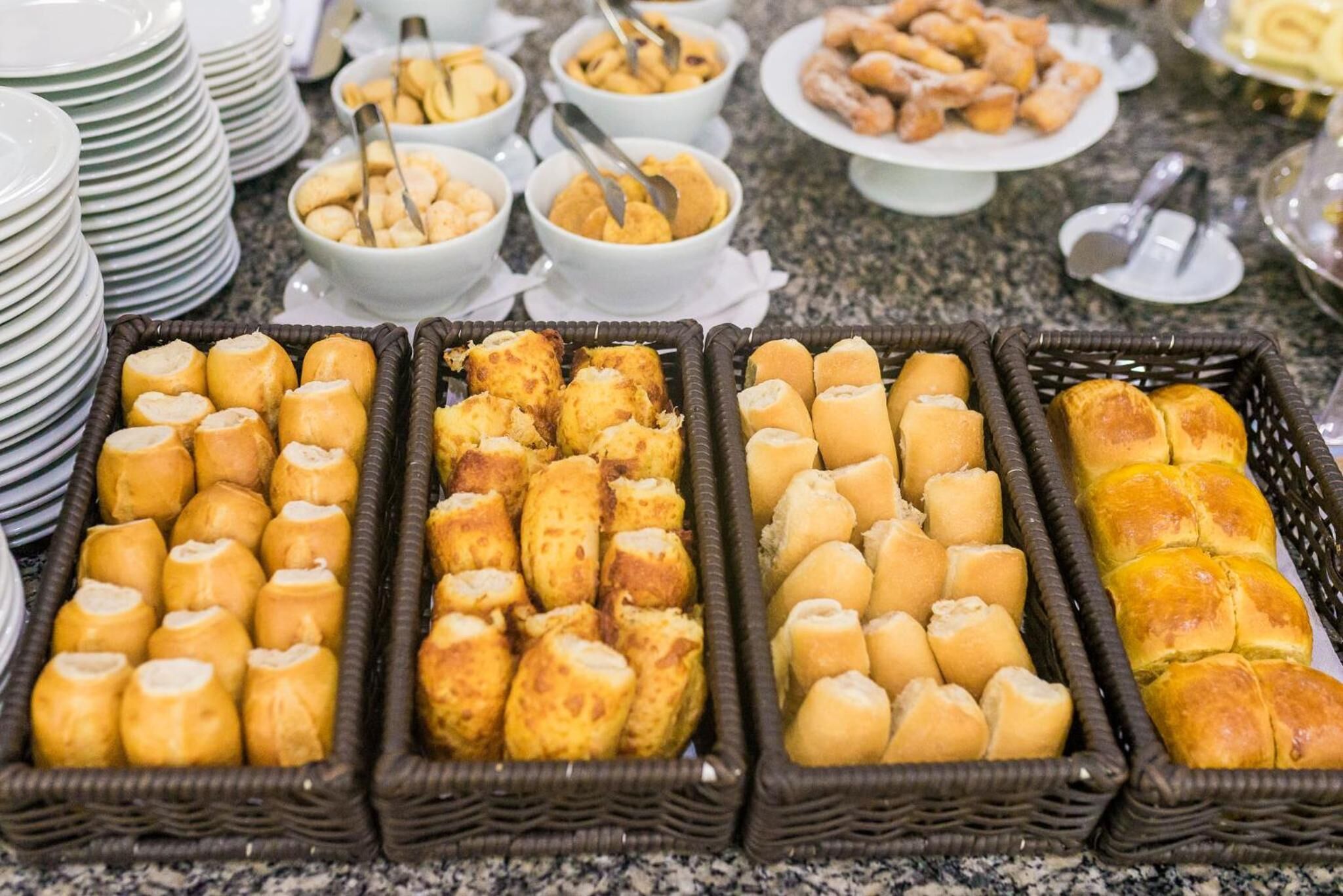 Un buffet con diversi cibi, tra cui panini, pasticcini e altre preparazioni da forno.