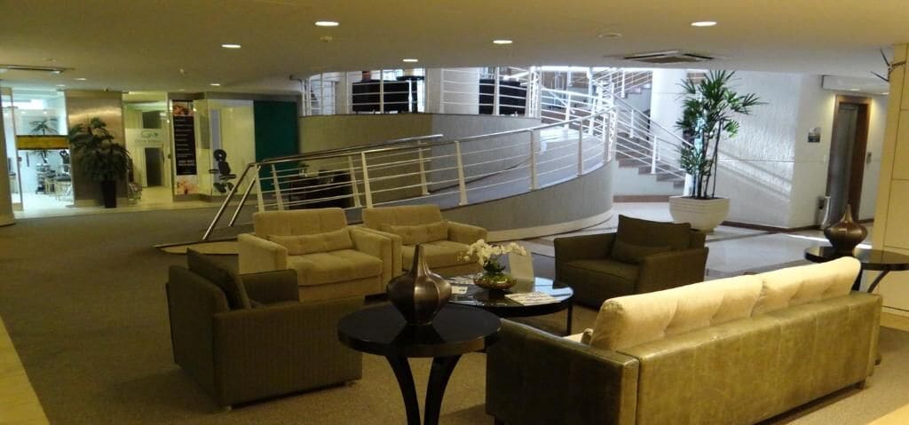 Um hall amplo com diversas áreas de estar e uma escada para um andar superior.