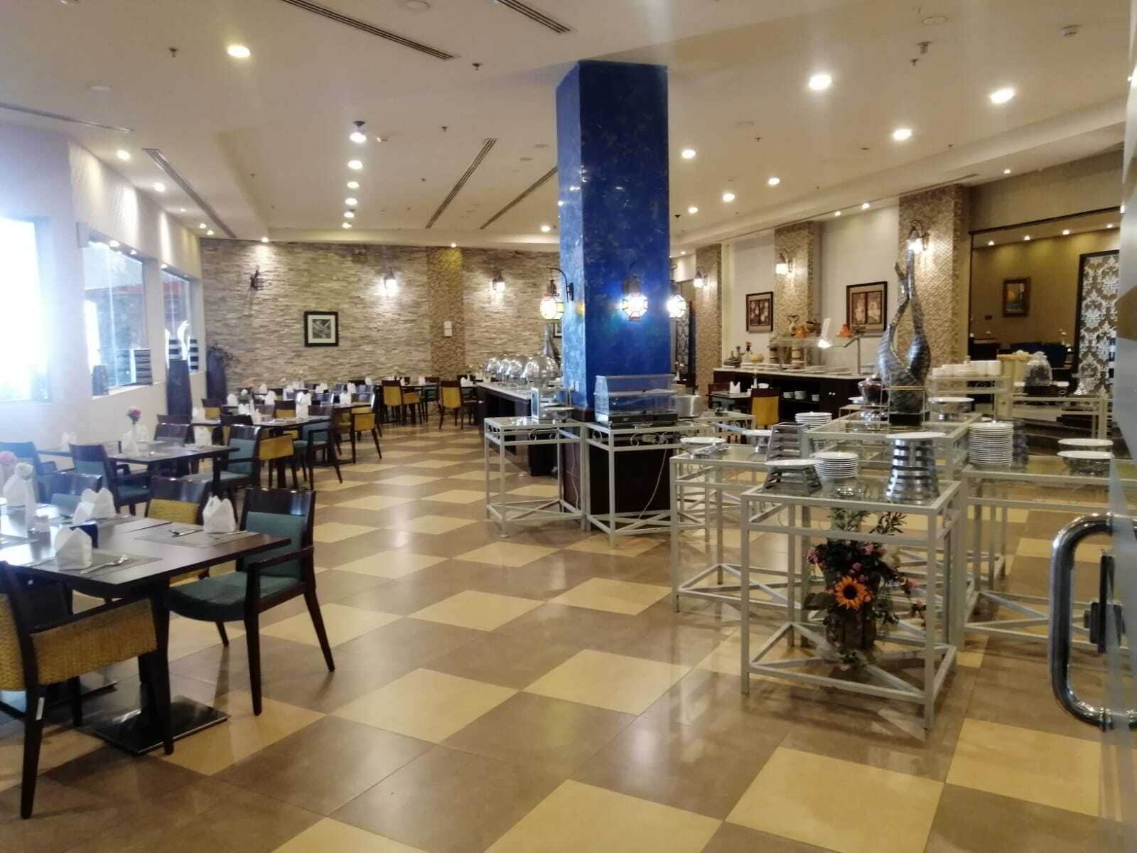 Un amplio comedor con piso a cuadros, varias mesas y sillas.