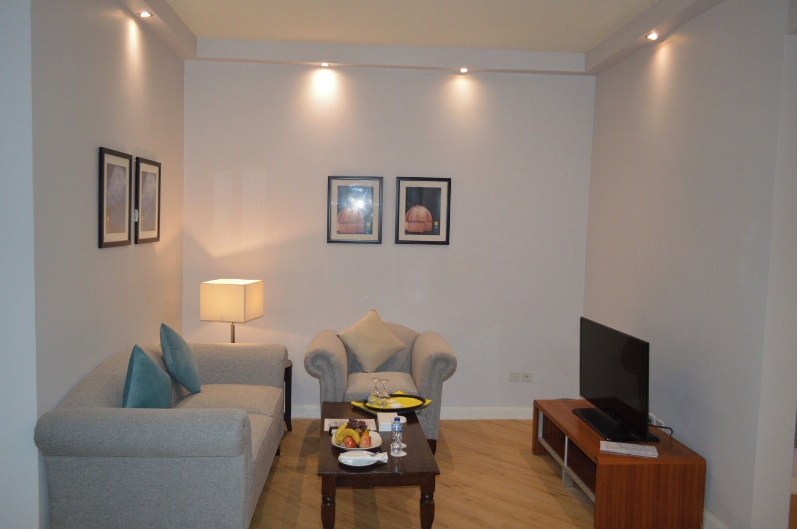A living room with a sofa, armchair, coffee table, lamp, and television.