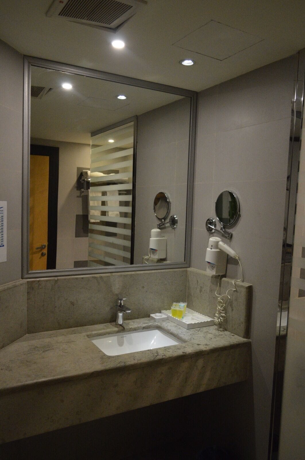 Un baño con un espejo grande, dos lavamanos y un secador de pelo.