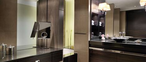 Un baño moderno con un espejo grande, paneles de madera oscura y una encimera de vidrio.