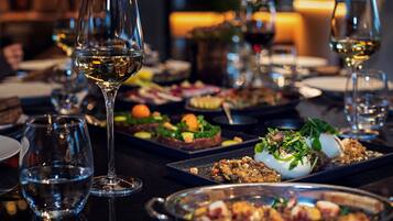 Mesa de jantar com vários copos de vinho e diversos pratos, indicando um ambiente de restaurante.