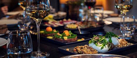 Una mesa de comedor con varias copas de vino y diferentes platos, indicando un ambiente de restaurante.