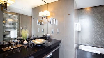Un bagno moderno con un piano di lavoro nero, un grande specchio e un faretto a parete.