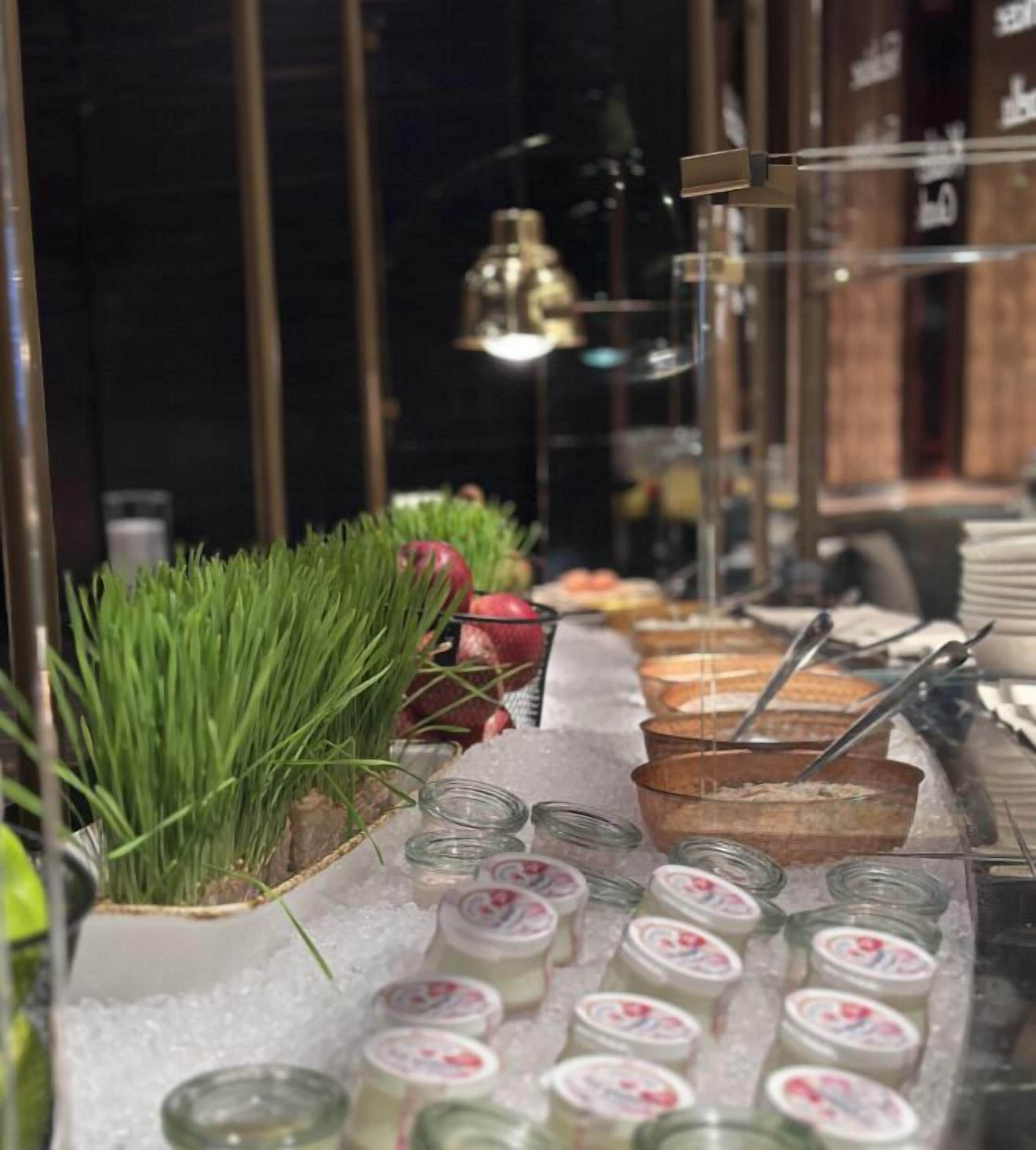 A buffet setup with various food items and a decorative plant.