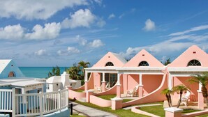 Un resort con edificios blancos y rosados, un área de piscina y vista al océano.