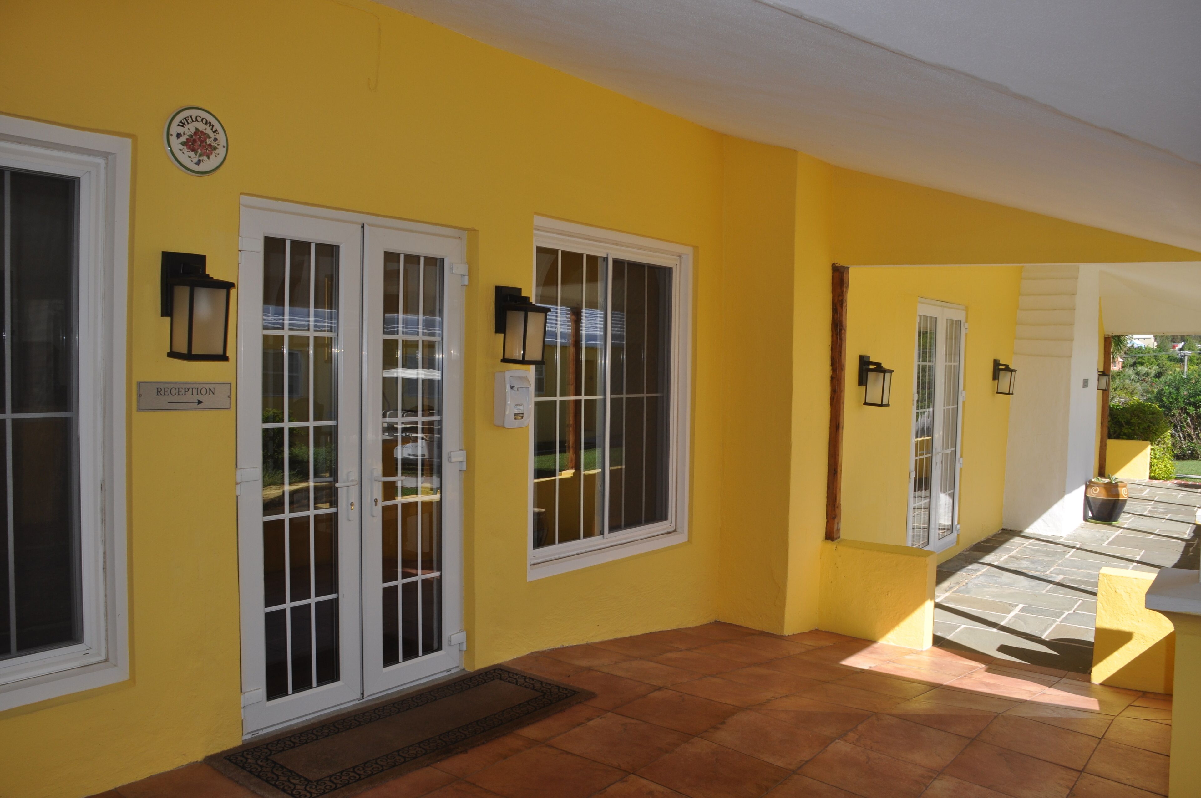 A yellow building with a reception area, a door with glass panels, and a tiled floor.