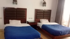 Two single beds with wooden headboards, white pillows, and blue bedspreads in a hotel room. - Carlton Luxury Resort (Sharm El Sheikh)