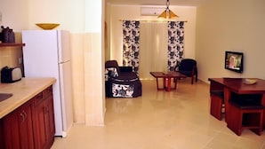 A compact kitchen with a refrigerator, toaster, and a bowl on the counter. A dining area with a table and chairs is visible in the background. - Carlton Luxury Resort (Sharm El Sheikh)
