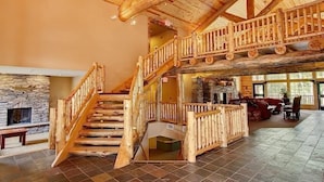 A spacious interior with a wooden staircase, stone fireplace, and a cozy seating area. - Whitefish Lodge and Suites (Crosslake)