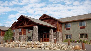 A log cabin-style building with a stone foundation and a large porch. - Whitefish Lodge and Suites (Crosslake)
