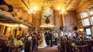 A wedding ceremony in a log cabin with a stone wall and a mounted deer head. - Whitefish Lodge and Suites (Crosslake)