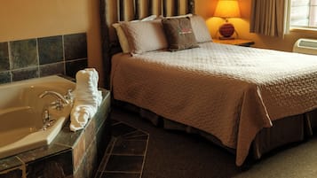 A hotel room with a bed, a nightstand, a lamp, a bathroom with a bathtub, and a window with curtains.