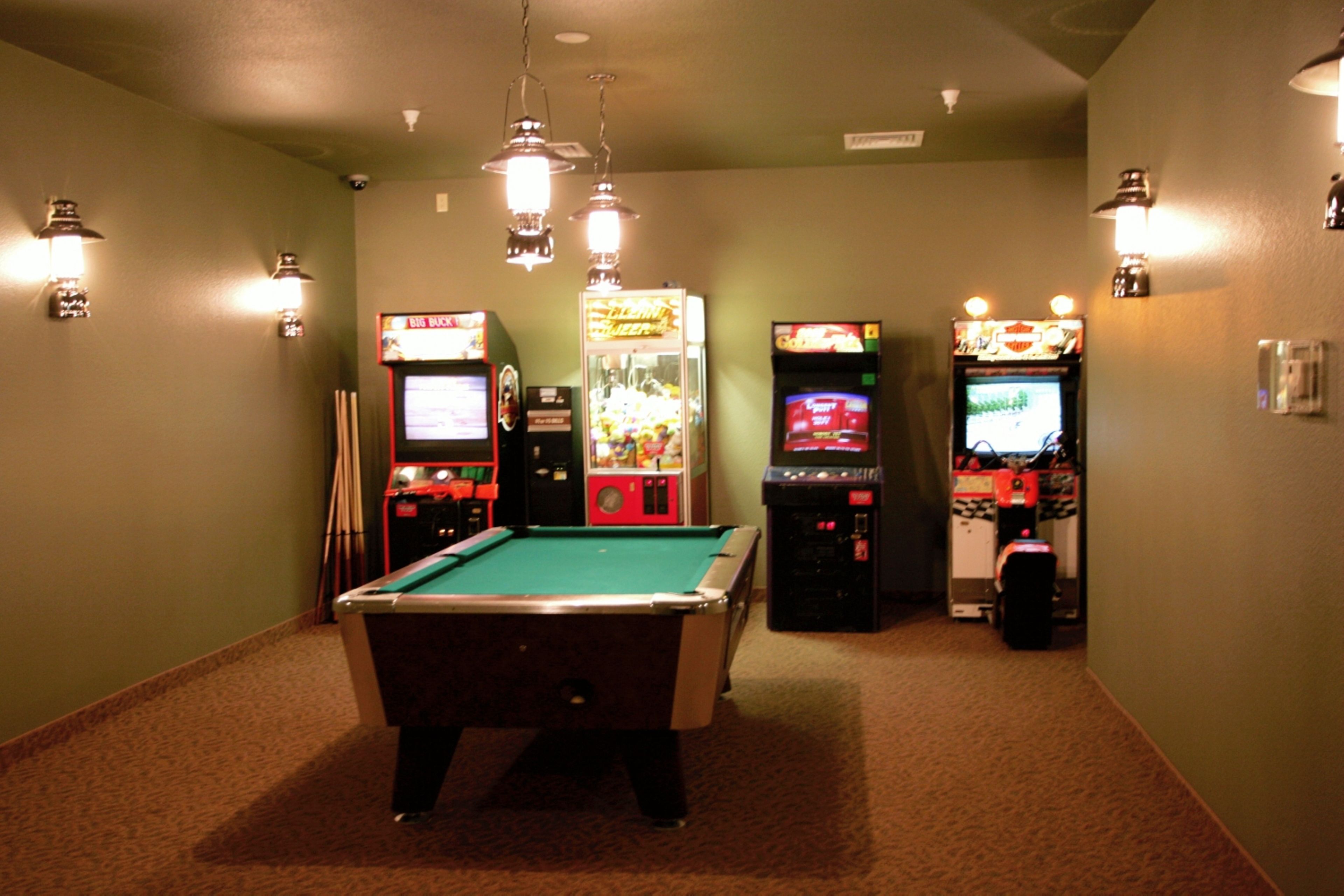 Taula de bitlles en una sala amb parets verdes i moqueta. Hi ha jocs recreatius al costat dret de la sala.