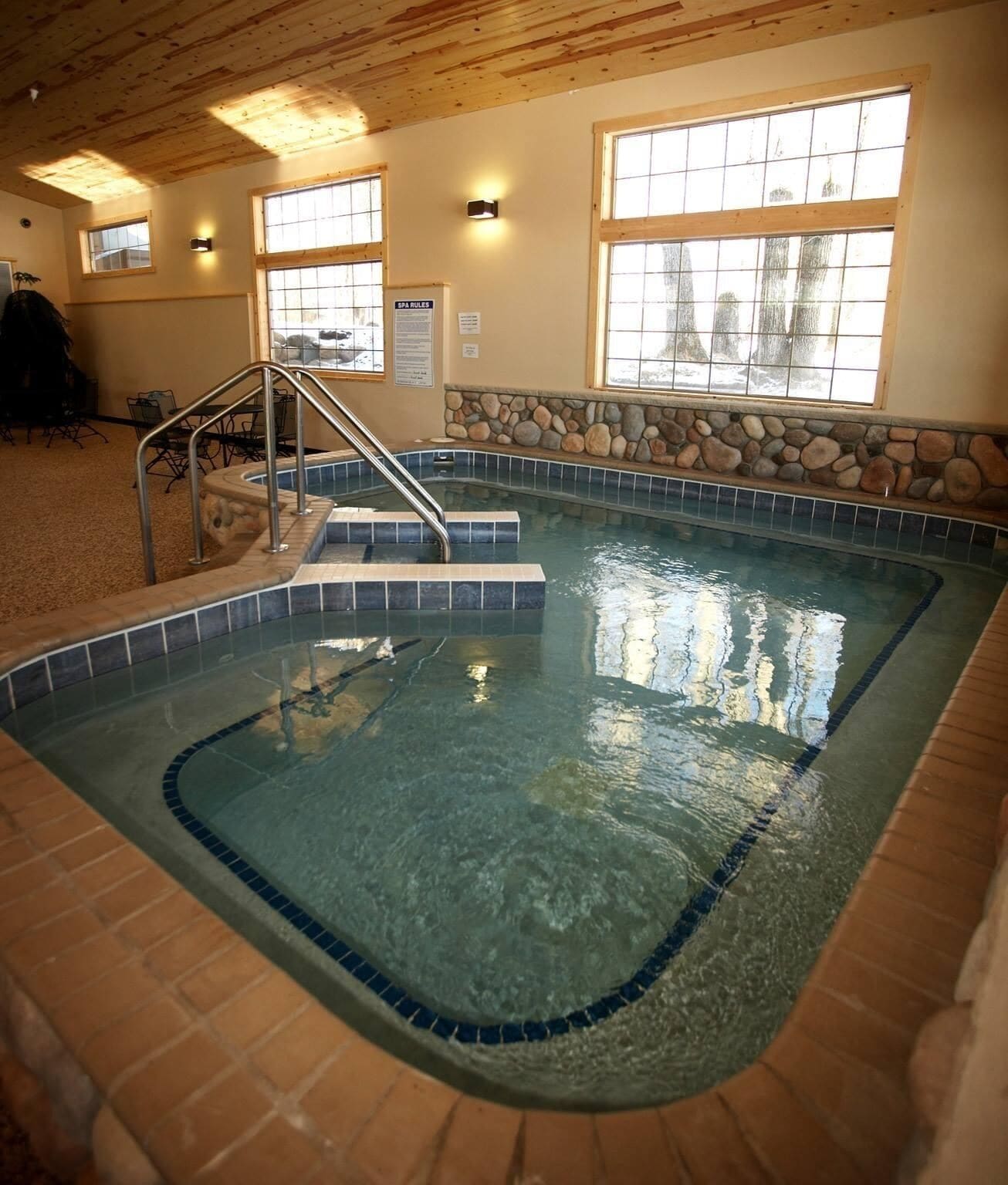 Una piscina interior amb aigua cristal·lina, parets de pedra i sostre de fusta.