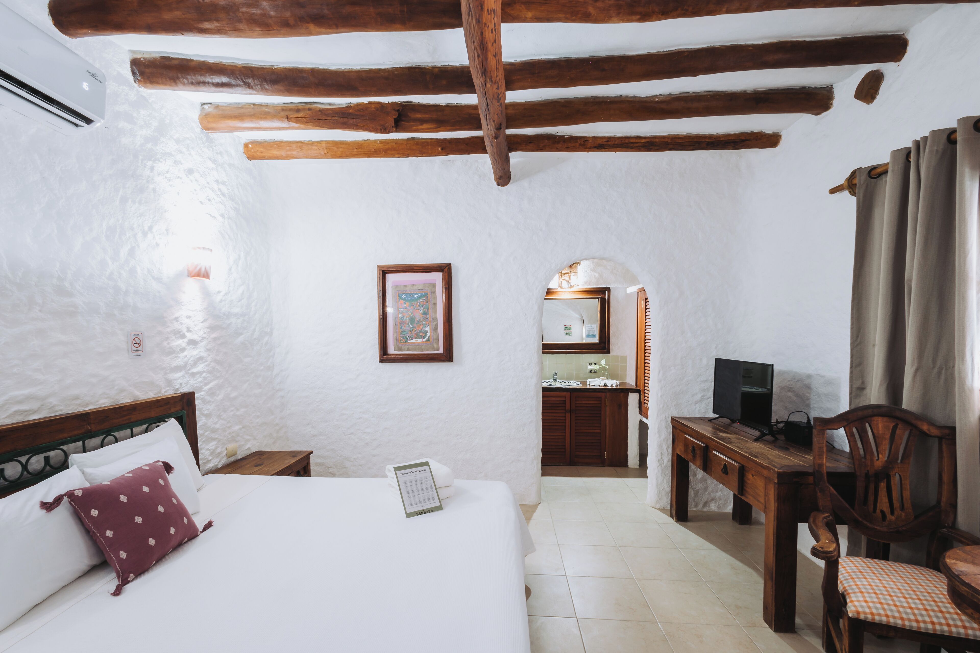 Un dormitorio con cama, escritorio, silla y televisor.