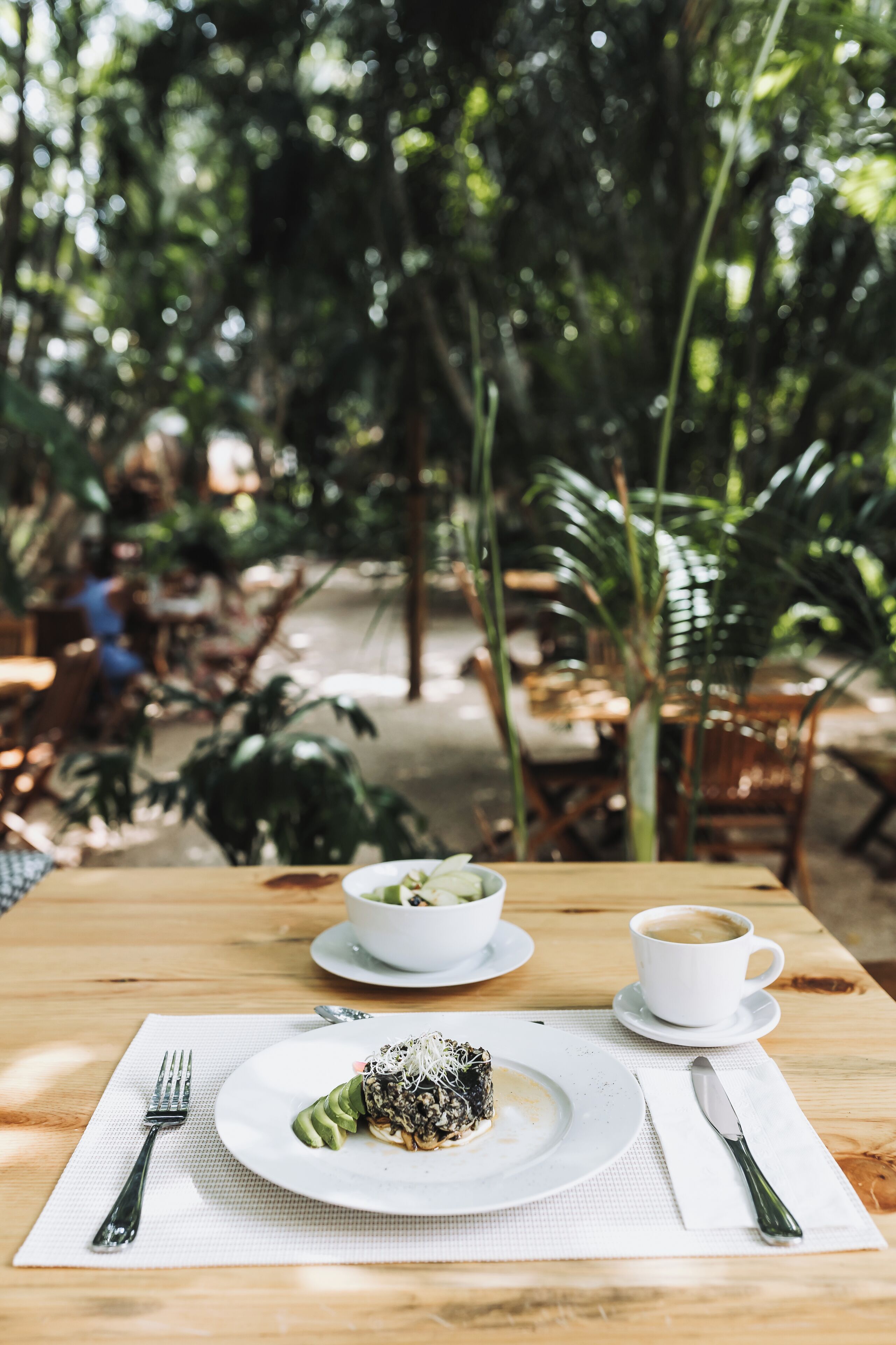 Una mesa con un plato de comida, una taza de café y un tenedor y un cuchillo.