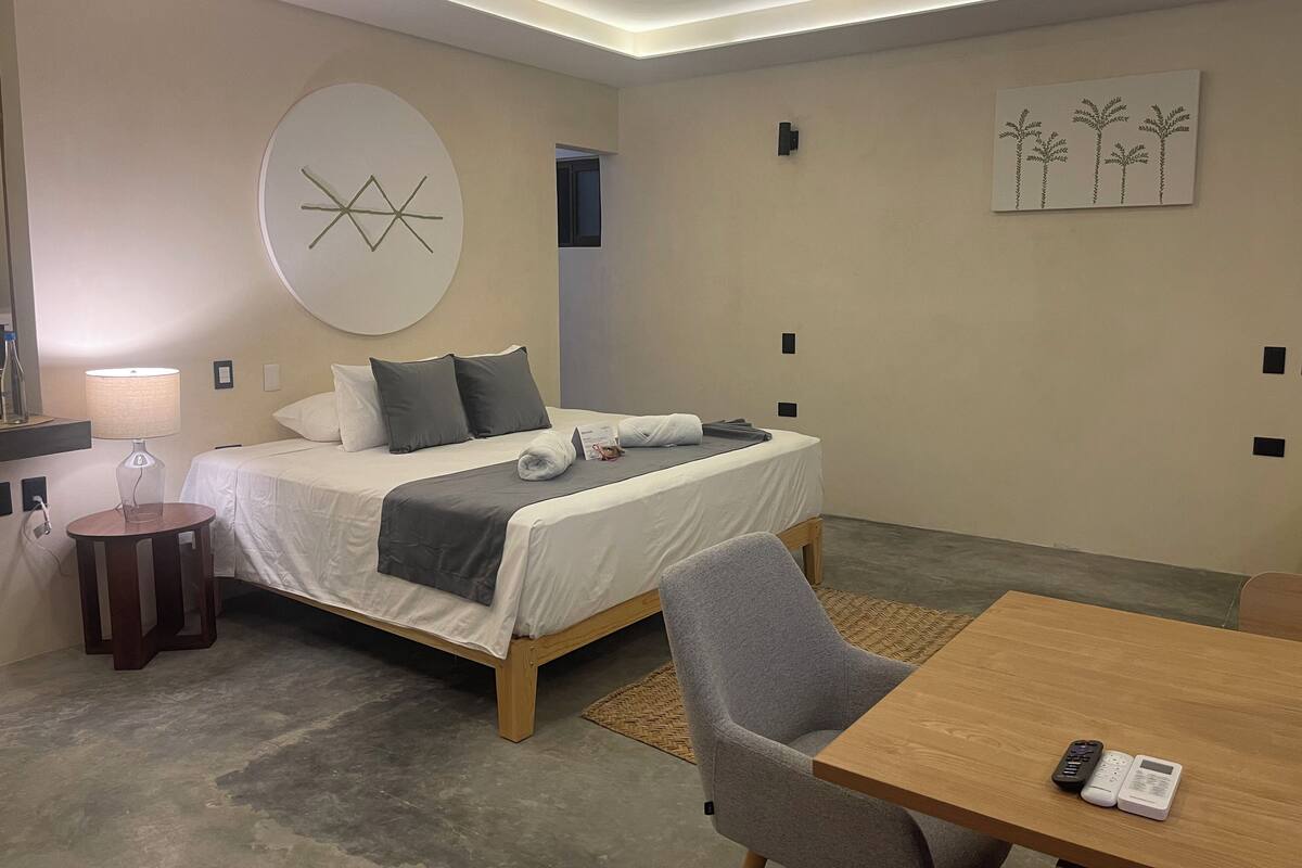 Ein modernes Hotelzimmer mit Bett, Schreibtisch, Stuhl und Lampe.