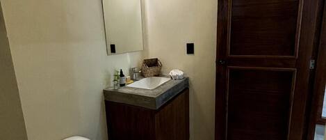 A bathroom with a toilet, sink, mirror, and wooden door.