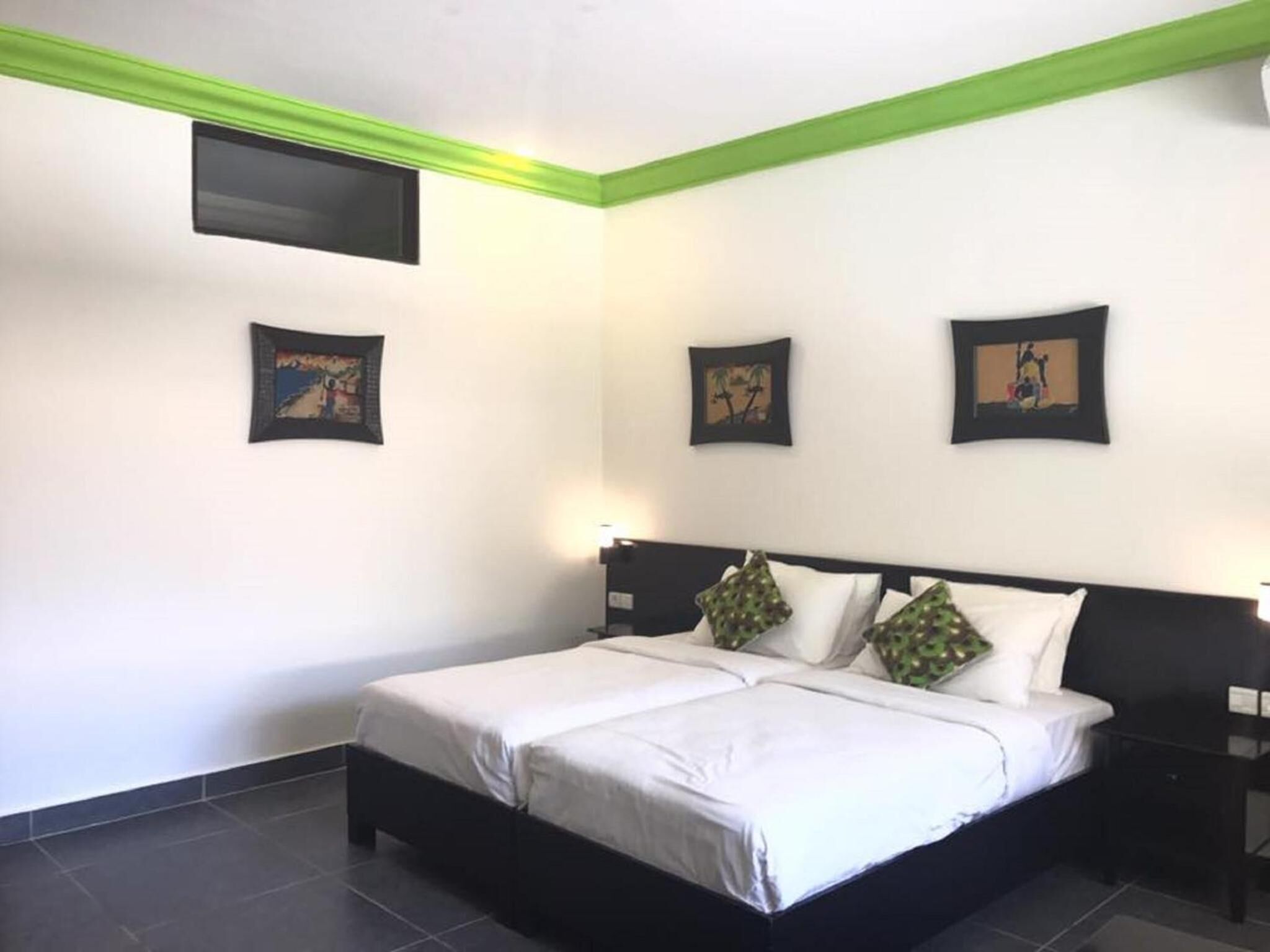 A hotel room with a large bed, two bedside tables, and three framed pictures on the wall.