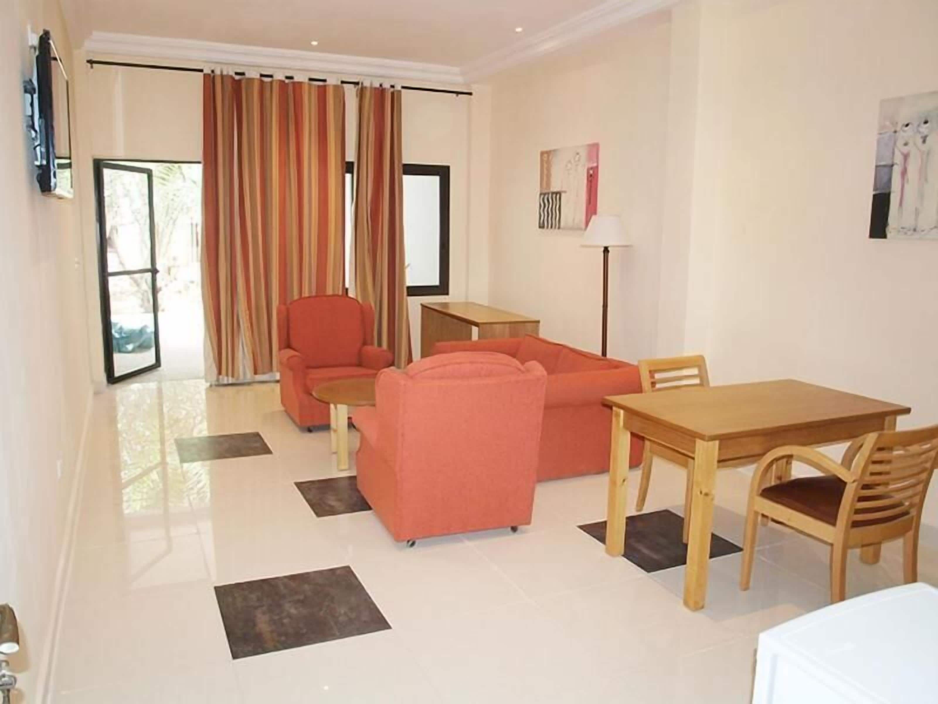 A modern living room with a sofa set, a dining table, and a chair.