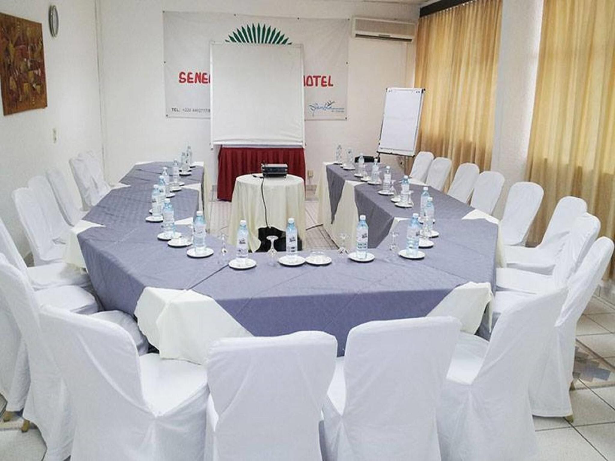 A conference room with a round table, white chairs, and a whiteboard.