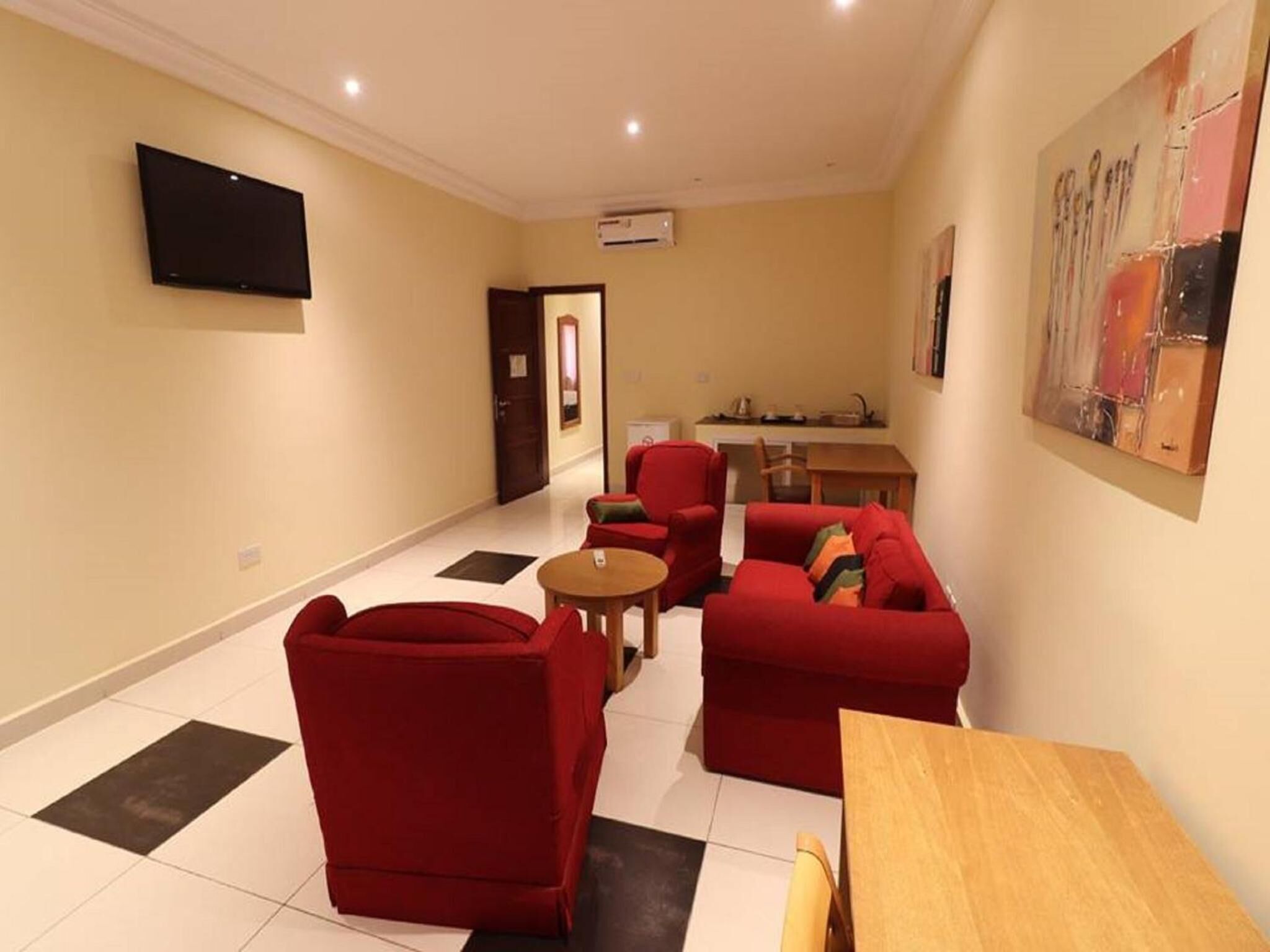 A living room with red furniture, a flat-screen TV, and a painting on the wall.