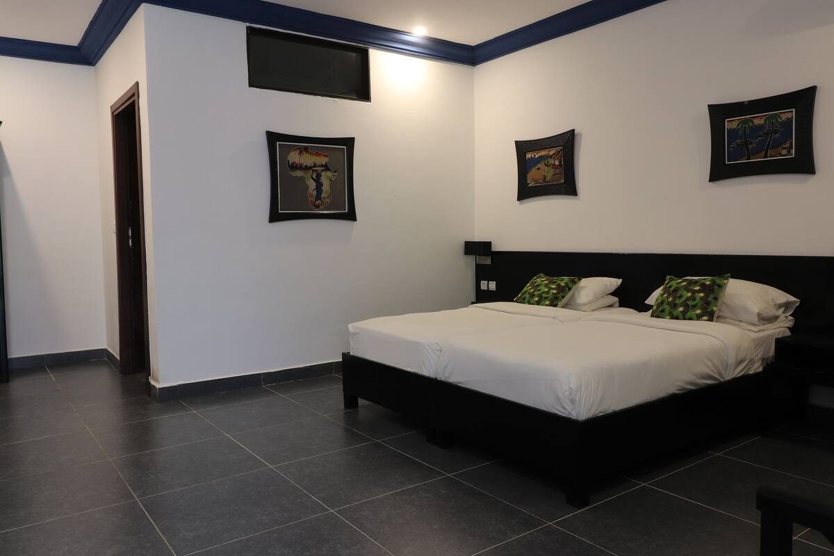 Ein Schlafzimmer mit einem Bett, einer Tür und drei gerahmten Bildern an der Wand.