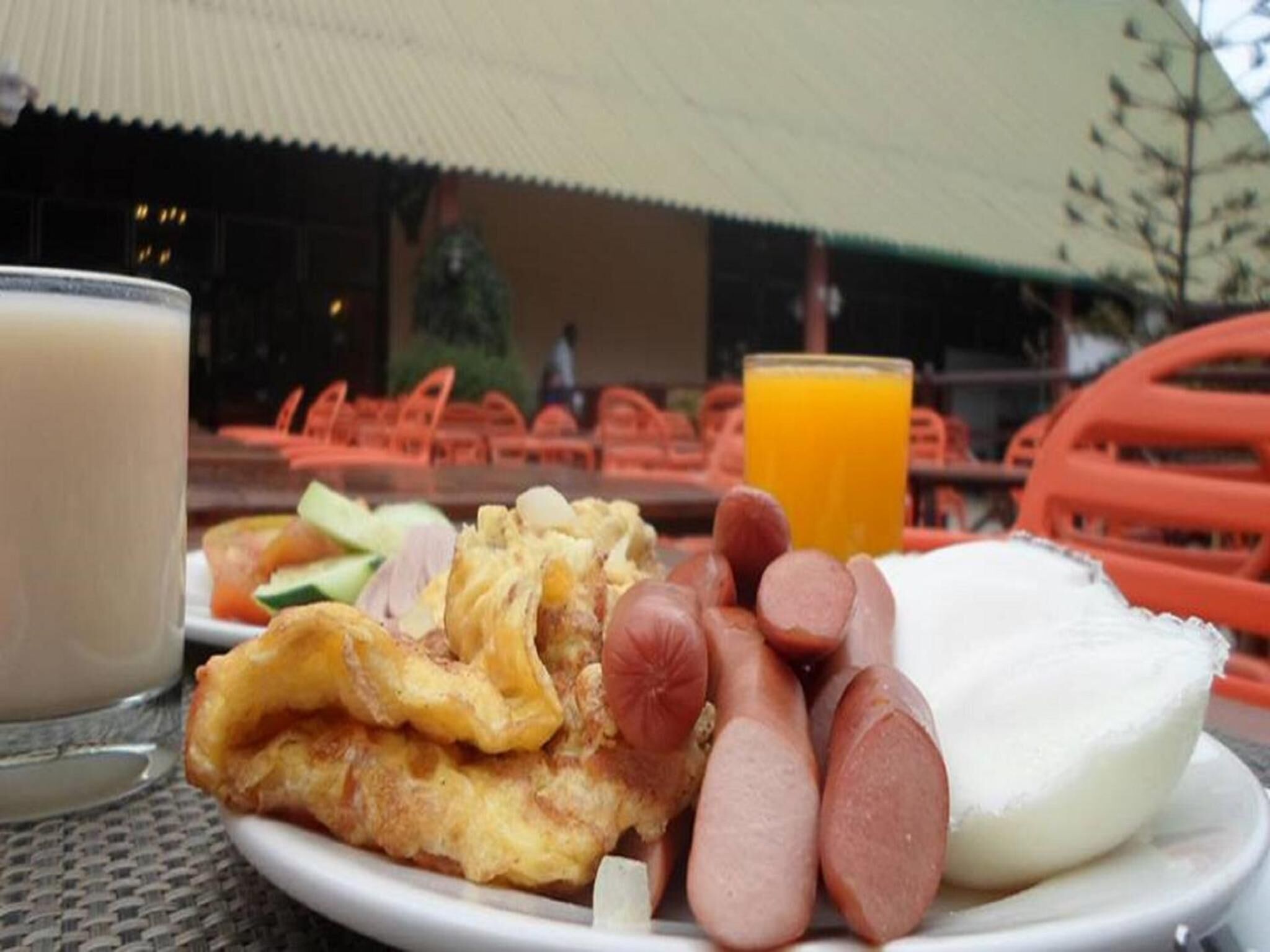 A breakfast plate with eggs, sausages, and a glass of orange juice.