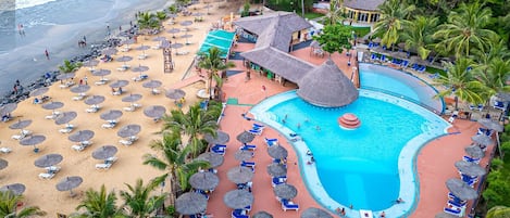 Un complexe hôtelier doté d’une piscine, d’une plage et de palmiers.
