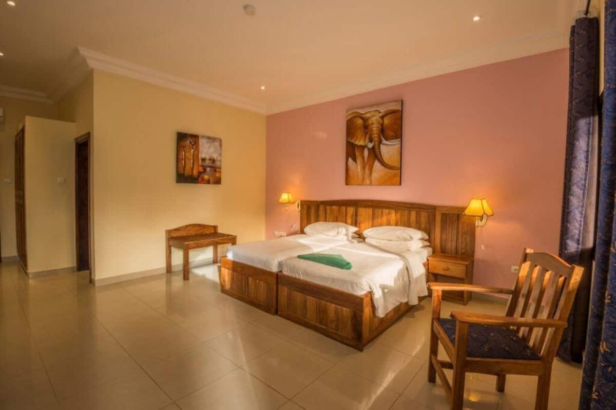 Ein Hotelzimmer mit einem Holzbett, zwei Nachttischen, einem Sessel und einem Bild an der Wand.