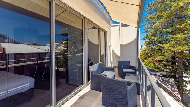 A balcony with glass doors, wicker furniture, and a view of the cityscape. - New Haus Managed by Hougoumont (Fremantle)