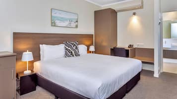 A hotel room with a large bed, two bedside tables with lamps, a wardrobe, and a painting on the wall.