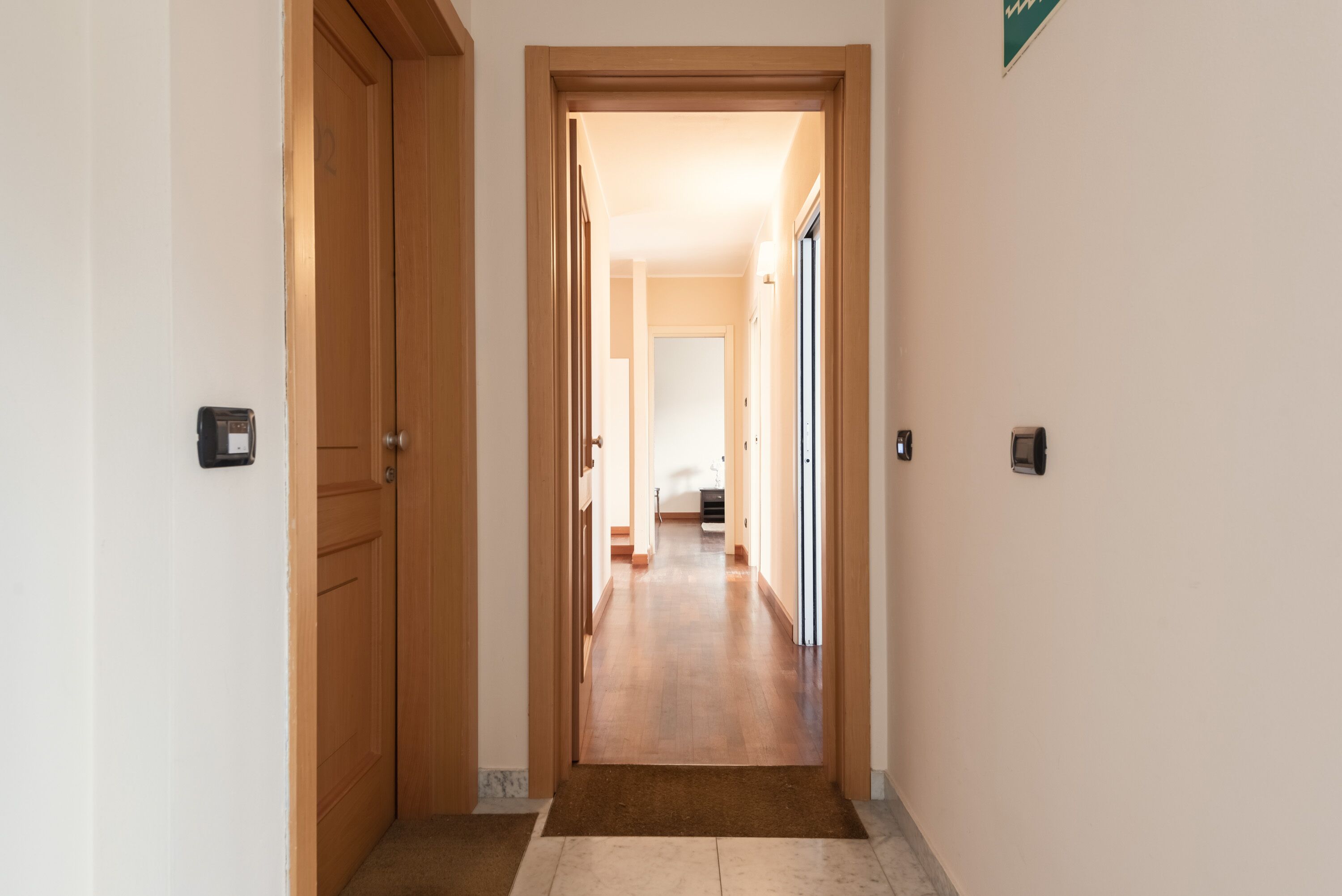 Un pasillo con puertas de madera, suelo alfombrado y pared de color claro.