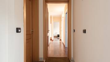Un pasillo con puertas de madera, suelo alfombrado y pared de color claro.