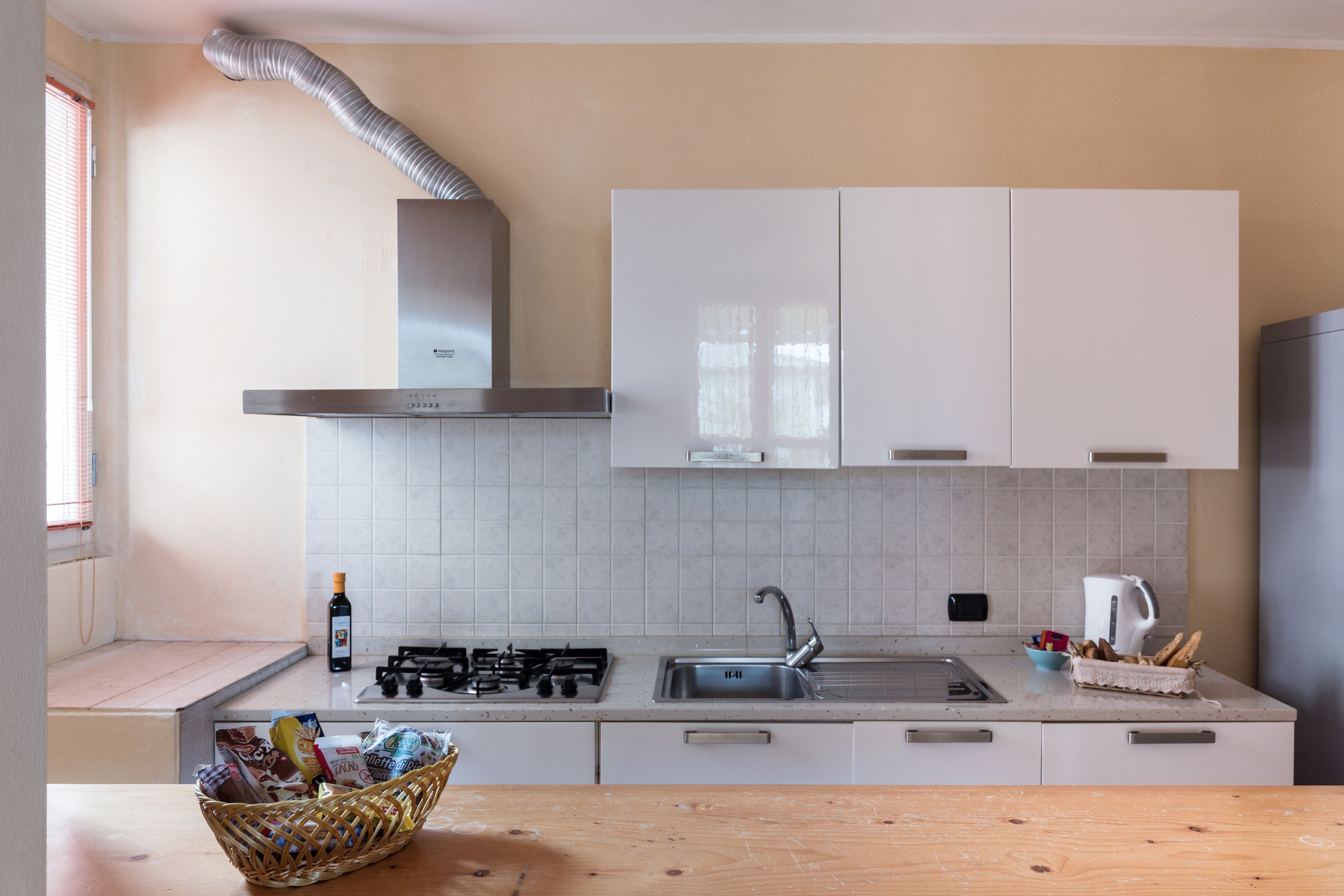 Een moderne keuken met witte kasten, een gasfornuis, een spoelbak en een houten aanrecht.