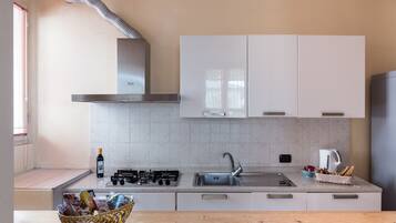 Een moderne keuken met witte kasten, een gasfornuis, een spoelbak en een houten aanrecht.