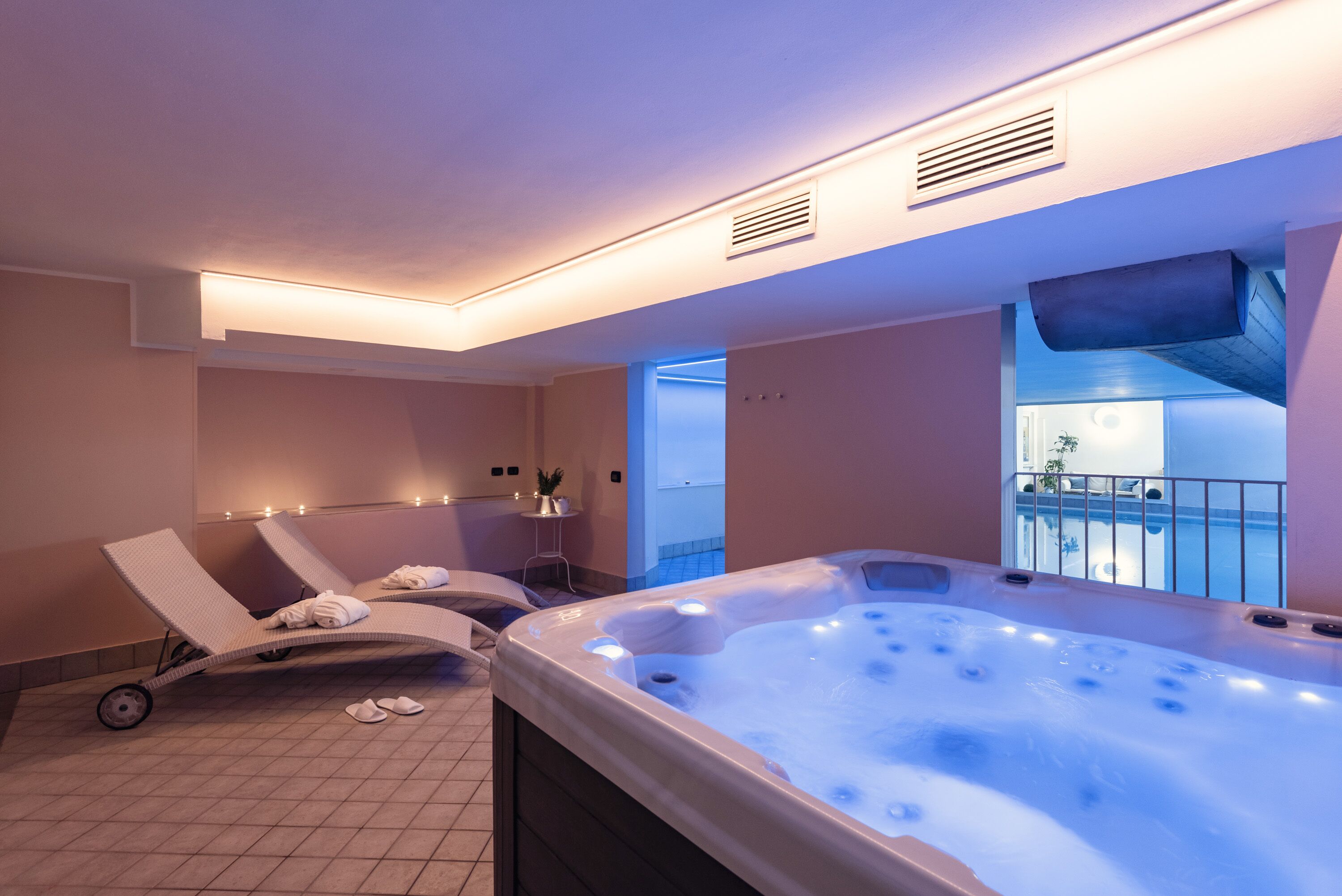 Ein Wellnessbereich mit Whirlpool, Liegestühlen und Blick auf einen Pool.