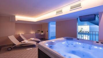 Ein Wellnessbereich mit Whirlpool, Liegestühlen und Blick auf einen Pool.