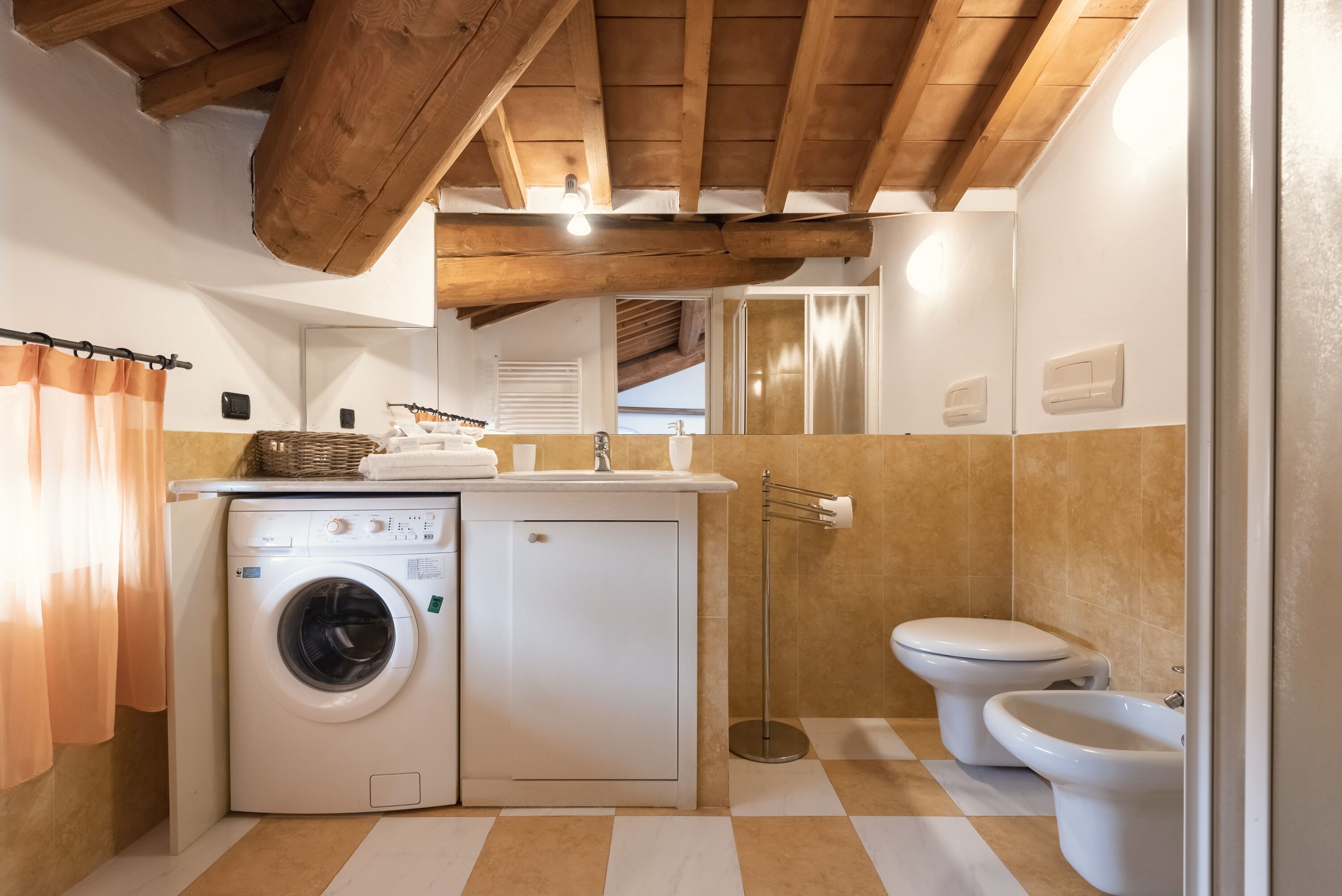 Een kleine badkamer met een wasmachine, toilet en een douchetoilet.